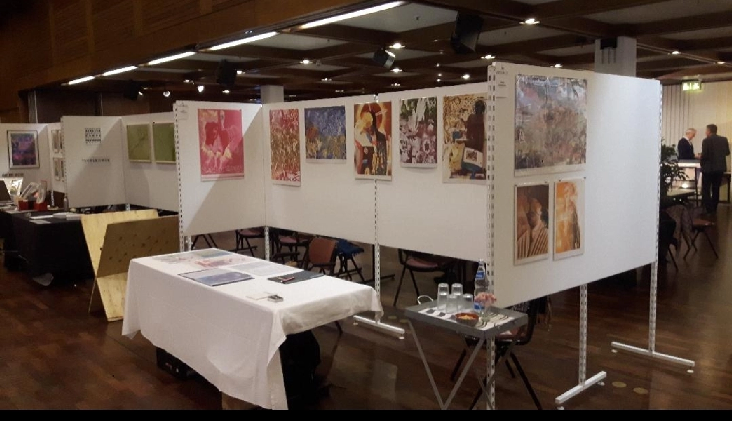 Artloch Prod. - art - Dieses Bild zeigt den Aufbau einer Kunstausstellung mit mehreren Gemälden, die in einer großen Halle an weißen modularen Präsentationswänden hängen.